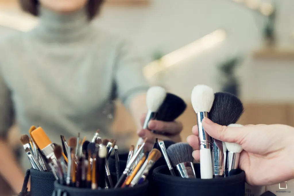 Makeup artist selecting brushes from a professional kit